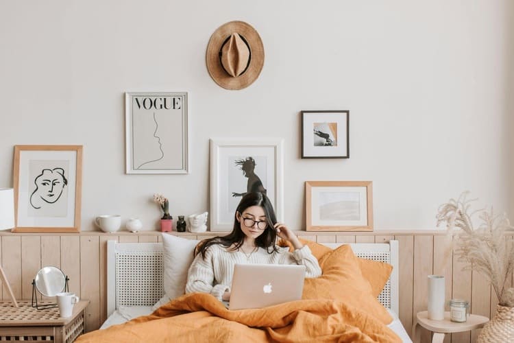 a woman working on laptop in her bed in a decorated room