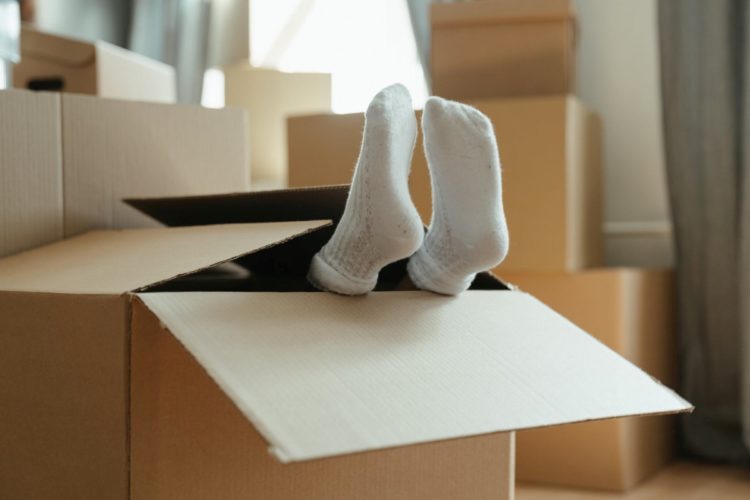 A person relaxing inside of a box with his/her feet out of the box.