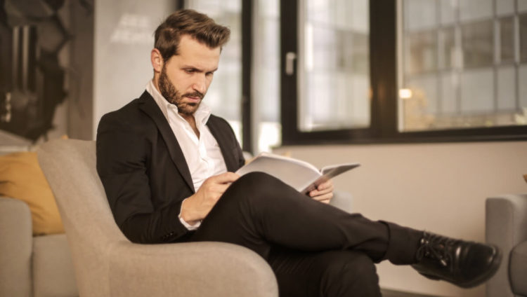 Man in Black Suit Reading Fashion Magazine