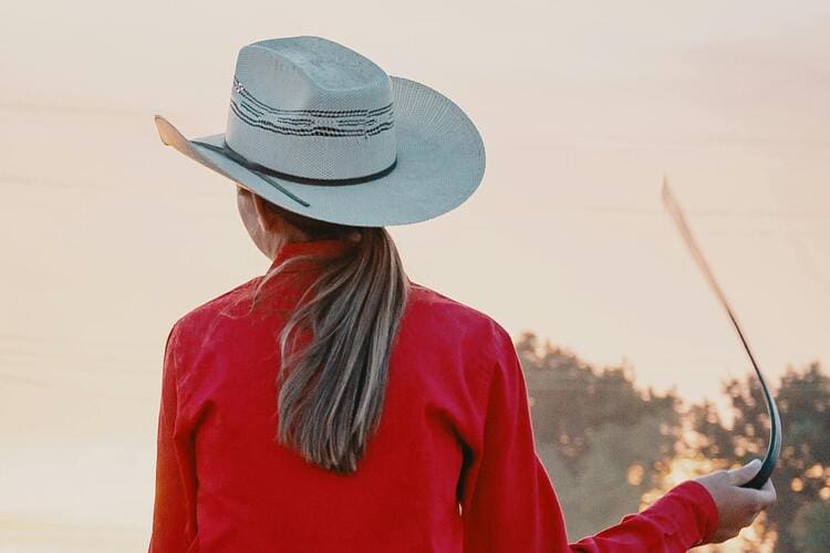 Woman Wearing White Cowboy Hat And Red Top Riding On Horse